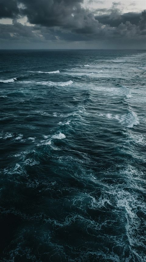 Cinematic film still of calm turquoise ocean with gentle waves, high-angle view from above, moody dark tones, dramatic lighting, 9:16 aspect ratio