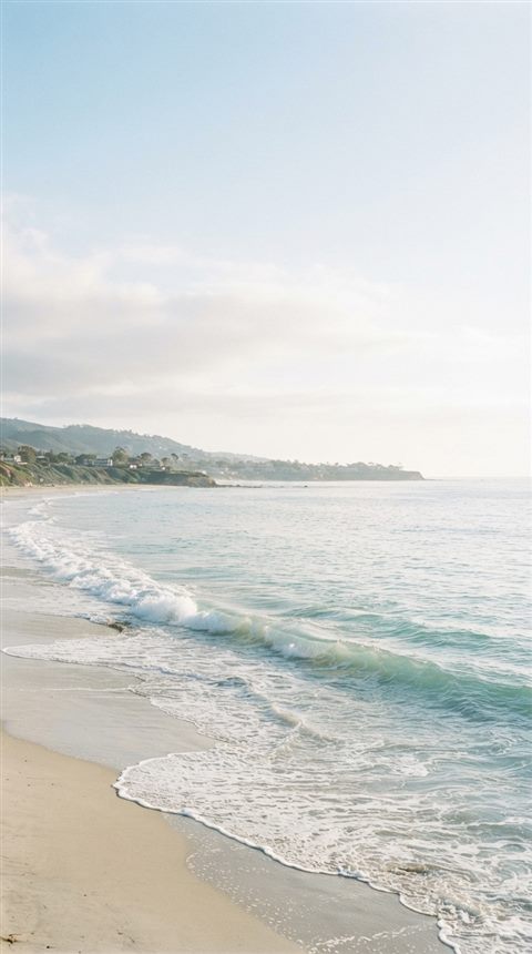 Cinematic film still of ocean waves, wide shot with open space at the top for text, soft pastel colors, bright and cozy, 9:16 aspect ratio