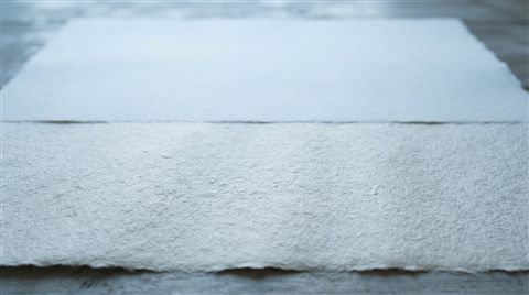 Photorealistic photo of paper texture, wide shot with open space at the top for text, cool blue tones, quiet atmosphere, 16:9 aspect ratio