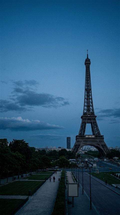 Cinematic film still of the Eiffel Tower in Paris, wide shot with open space at the top for text, cool blue tones, quiet atmosphere, 9:16 aspect ratio