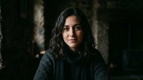 Photorealistic photo of portrait of a fictional person with a natural expression, centered subject with a simple uncluttered composition, moody dark tones, dramatic lighting, 16:9 aspect ratio