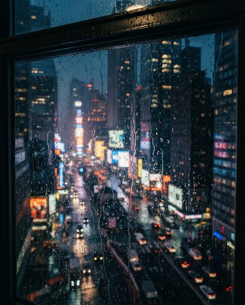 Cinematic film still of Raindrops falling on a window pane with a blurred urban view in the background, high-angle view from above, vivid colors, high contrast, energetic, 4:5 aspect ratio