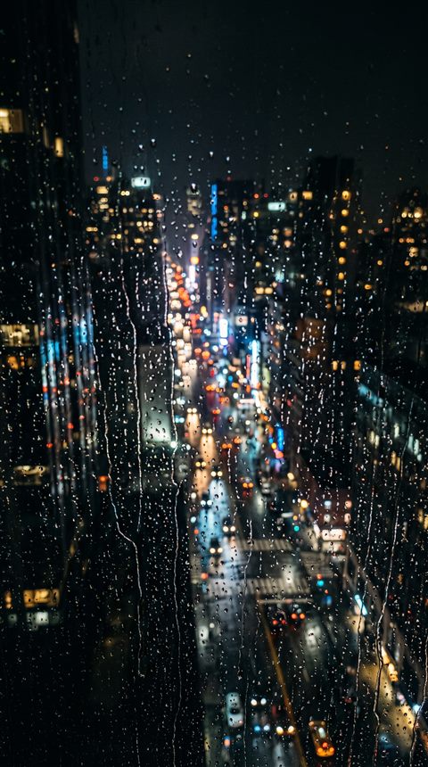 Photorealistic photo of rainy window at night with blurred city lights outside, high-angle view from above, moody dark tones, dramatic lighting, 9:16 aspect ratio