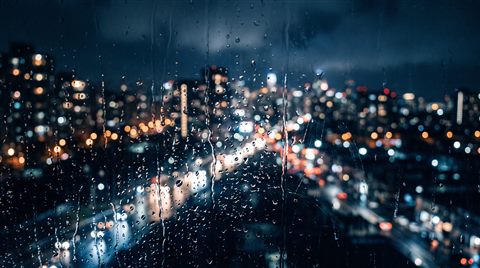 Photorealistic photo of rainy window at night with blurred city lights outside, close-up detail with shallow depth of field, cool blue tones, quiet atmosphere, 16:9 aspect ratio