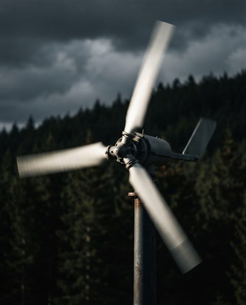 Photorealistic photo of small wind turbine blades spinning under bright sunlight, close-up detail with shallow depth of field, moody dark tones, dramatic lighting, 4:5 aspect ratio