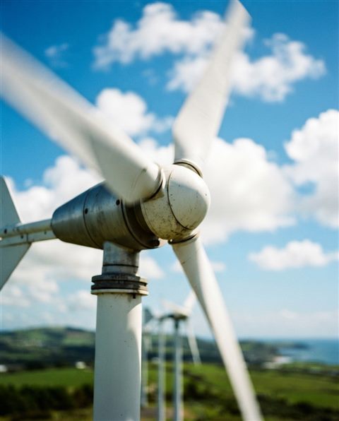 Cinematic film still of small wind turbine blades spinning under bright sunlight, close-up detail with shallow depth of field, vivid colors, high contrast, energetic, 4:5 aspect ratio