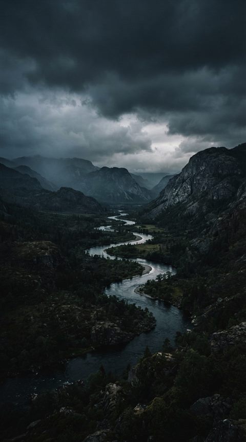 Cinematic film still of winding river through a valley, wide shot with open space at the top for text, moody dark tones, dramatic lighting, 9:16 aspect ratio