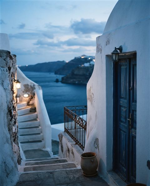 Cinematic film still of white houses of Santorini above the sea, close-up detail with shallow depth of field, cool blue tones, quiet atmosphere, 4:5 aspect ratio