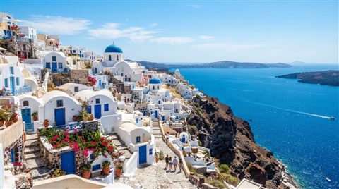 Photorealistic photo of white houses of Santorini above the sea, centered subject with a simple uncluttered composition, vivid colors, high contrast, energetic, 16:9 aspect ratio