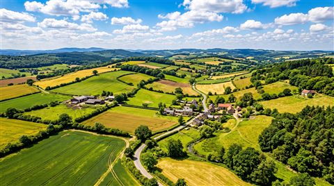 Photorealistic photo of peaceful countryside scenery with rolling hills, high-angle view from above, vivid colors, high contrast, energetic, 16:9 aspect ratio