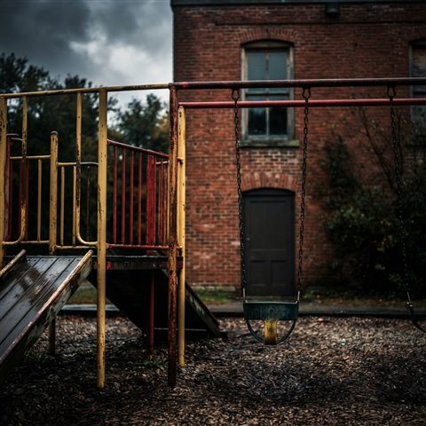 Photorealistic photo of a school building with a playground, close-up detail with shallow depth of field, moody dark tones, dramatic lighting, 1:1 aspect ratio
