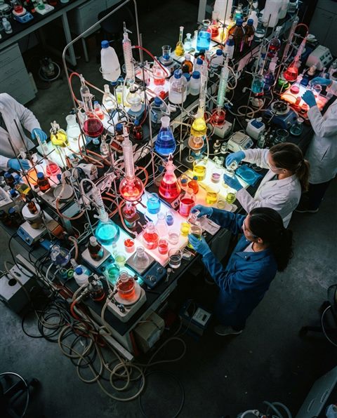 Cinematic film still of science lab beakers with colorful liquids, high-angle view from above, vivid colors, high contrast, energetic, 4:5 aspect ratio