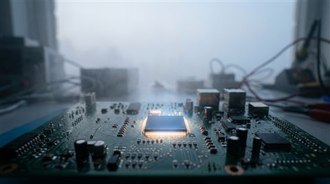 Photorealistic photo of a glowing microchip on a circuit board, wide shot with open space at the top for text, misty morning haze, dreamy, 16:9 aspect ratio