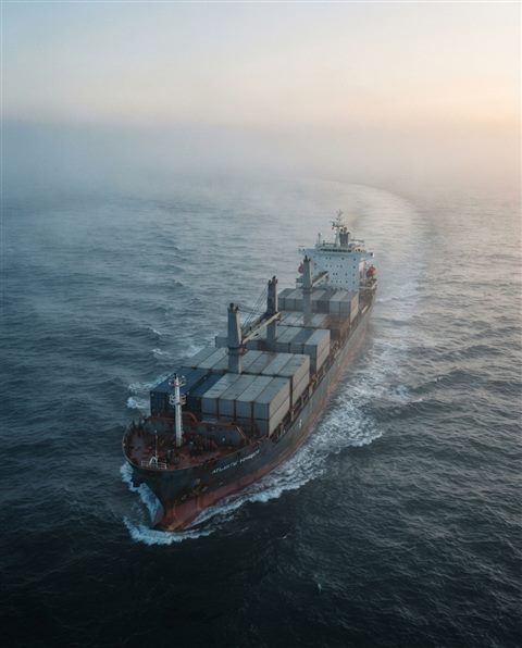 Cinematic film still of a large ship on the open sea, high-angle view from above, misty morning haze, dreamy, 4:5 aspect ratio