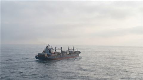Photorealistic photo of a large ship on the open sea, wide shot with open space at the top for text, misty morning haze, dreamy, 16:9 aspect ratio