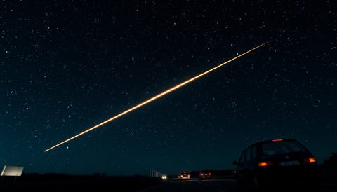 Cinematic film still of A brilliant shooting star streak across a dark night sky filled with countless bright stars, centered subject with a simple uncluttered composition, vivid colors, high contrast, energetic, 16:9 aspect ratio