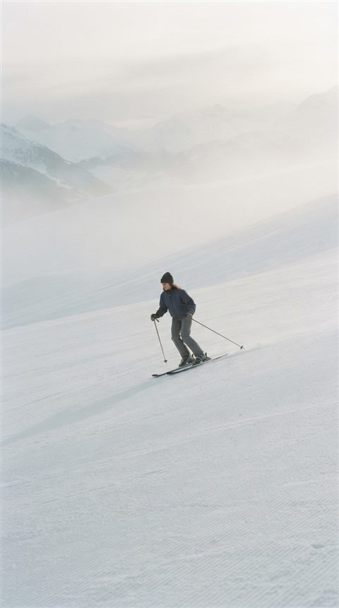 Cinematic film still of a snowy ski slope, centered subject with a simple uncluttered composition, misty morning haze, dreamy, 9:16 aspect ratio