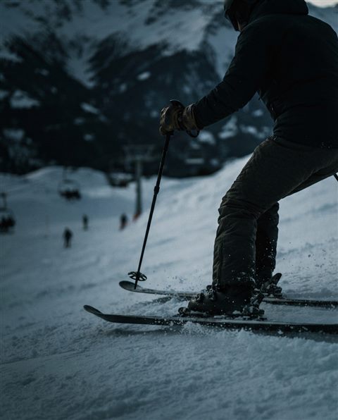 Cinematic film still of a snowy ski slope, close-up detail with shallow depth of field, moody dark tones, dramatic lighting, 4:5 aspect ratio