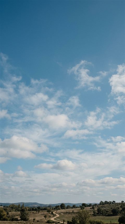 Cinematic film still of blue sky with soft clouds, wide shot with open space at the top for text, cool blue tones, quiet atmosphere, 9:16 aspect ratio