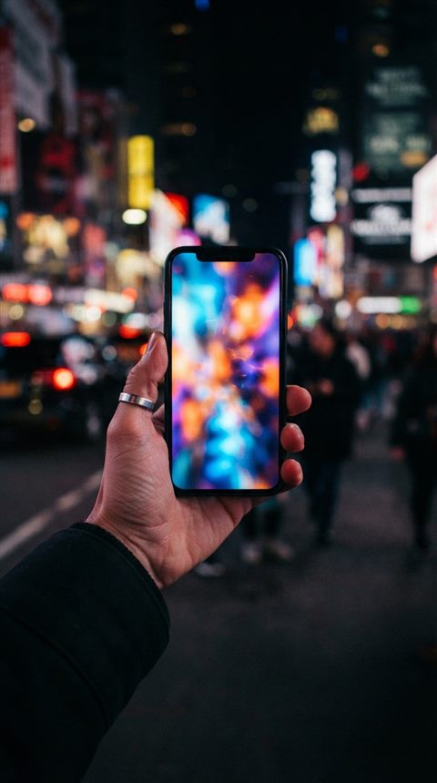 Cinematic film still of smartphone in hand, centered subject with a simple uncluttered composition, vivid colors, high contrast, energetic, 9:16 aspect ratio