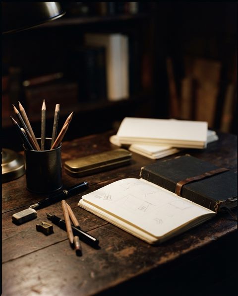 Cinematic film still of pencils, notebooks and stationery on a desk, close-up detail with shallow depth of field, moody dark tones, dramatic lighting, 4:5 aspect ratio