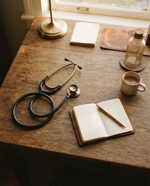 Cinematic film still of a stethoscope on a desk, high-angle view from above, warm golden light, calm mood, 4:5 aspect ratio