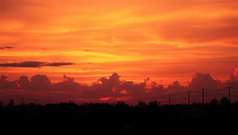 Photorealistic photo of A vibrant evening horizon with brilliant gradients of orange, pink, and purple clouds over a calm silhouette landscape., centered subject with a simple uncluttered composition, warm golden light, calm mood, 16:9 aspect ratio