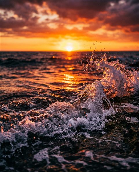 Fotograma de filme cinematográfico de pôr do sol sobre o mar, detalhe em close-up com profundidade de campo rasa, cores vivas, alto contraste, enérgico, proporção 4:5