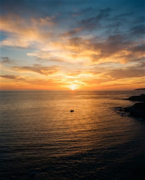 Cinematic film still of Realistic photo of a golden sunset over a calm ocean viewed from eye level, with empty sky space on top for text, horizontal landscape format, high-angle view from above, vivid colors, high contrast, energetic, 4:5 aspect ratio