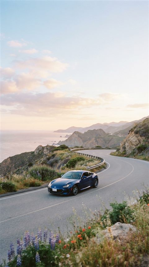 Cinematic film still of sleek generic sports car on an empty road, no brand badges, wide shot with open space at the top for text, soft pastel colors, bright and cozy, 9:16 aspect ratio