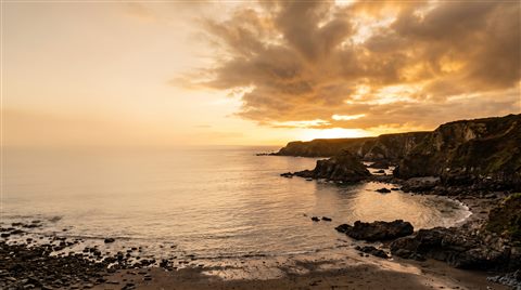 Photorealistic photo of bold dramatic background with empty space on the left half for a person and a title, wide shot with open space at the top for text, warm golden light, calm mood, 16:9 aspect ratio