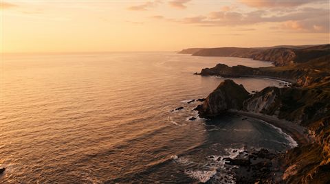 Cinematic film still of bold dramatic background with empty space on the left half for a person and a title, high-angle view from above, warm golden light, calm mood, 16:9 aspect ratio