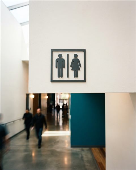 Cinematic film still of a clean and modern minimalist toilet sign pictogram on a white wall, wide shot with open space at the top for text, vivid colors, high contrast, energetic, 4:5 aspect ratio