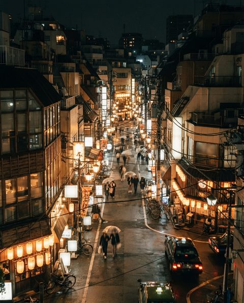 Cinematic film still of a Tokyo street at night, high-angle view from above, warm golden light, calm mood, 4:5 aspect ratio