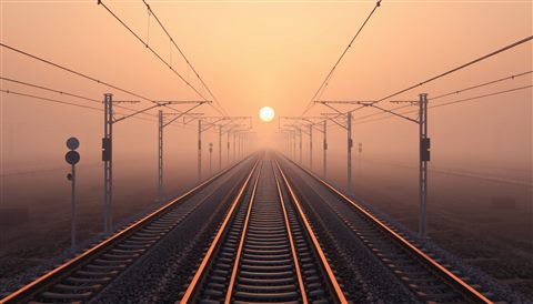 Soft 3D render of Empty railway tracks stretching into the distance under the warm glow of a sunset, high-angle view from above, misty morning haze, dreamy, 16:9 aspect ratio