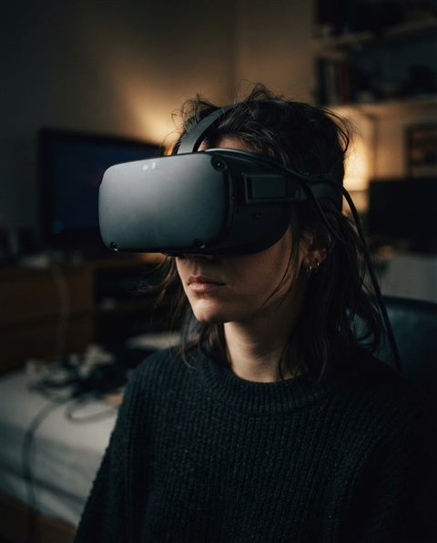 Cinematic film still of a person wearing a VR headset, close-up detail with shallow depth of field, moody dark tones, dramatic lighting, 4:5 aspect ratio