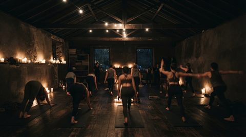 Photorealistic photo of yoga practice, wide shot with open space at the top for text, moody dark tones, dramatic lighting, 16:9 aspect ratio